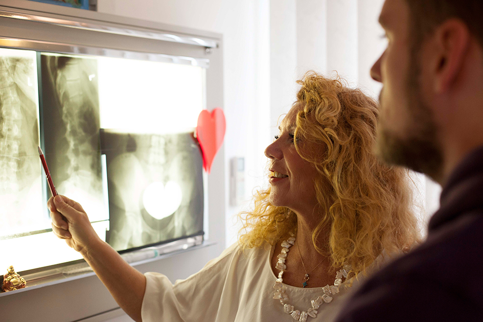 Carola Fischer analysiert Röntgenbilder im Gespräch mit einem Patienten. So erfahren Sie, was auf den Bildern wirklich zu sehen ist.